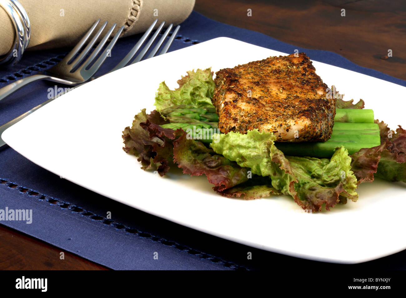 delicious grilled sea bass, seasoned with fine spices with asparagus and lettuce bed Stock Photo