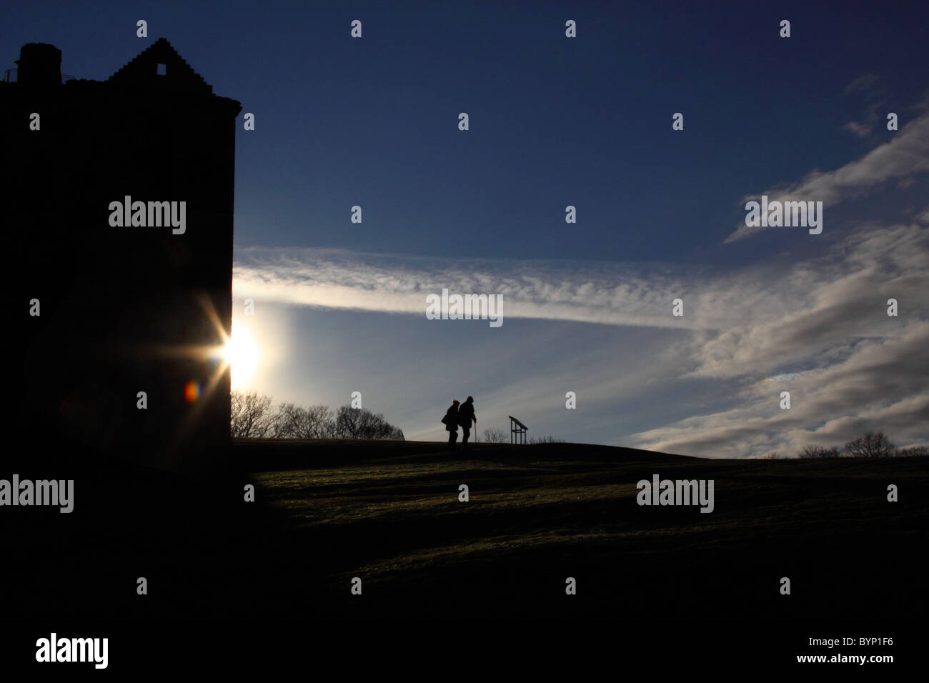 Silhouetted couple with the glare of the sun behind a building Stock Photo