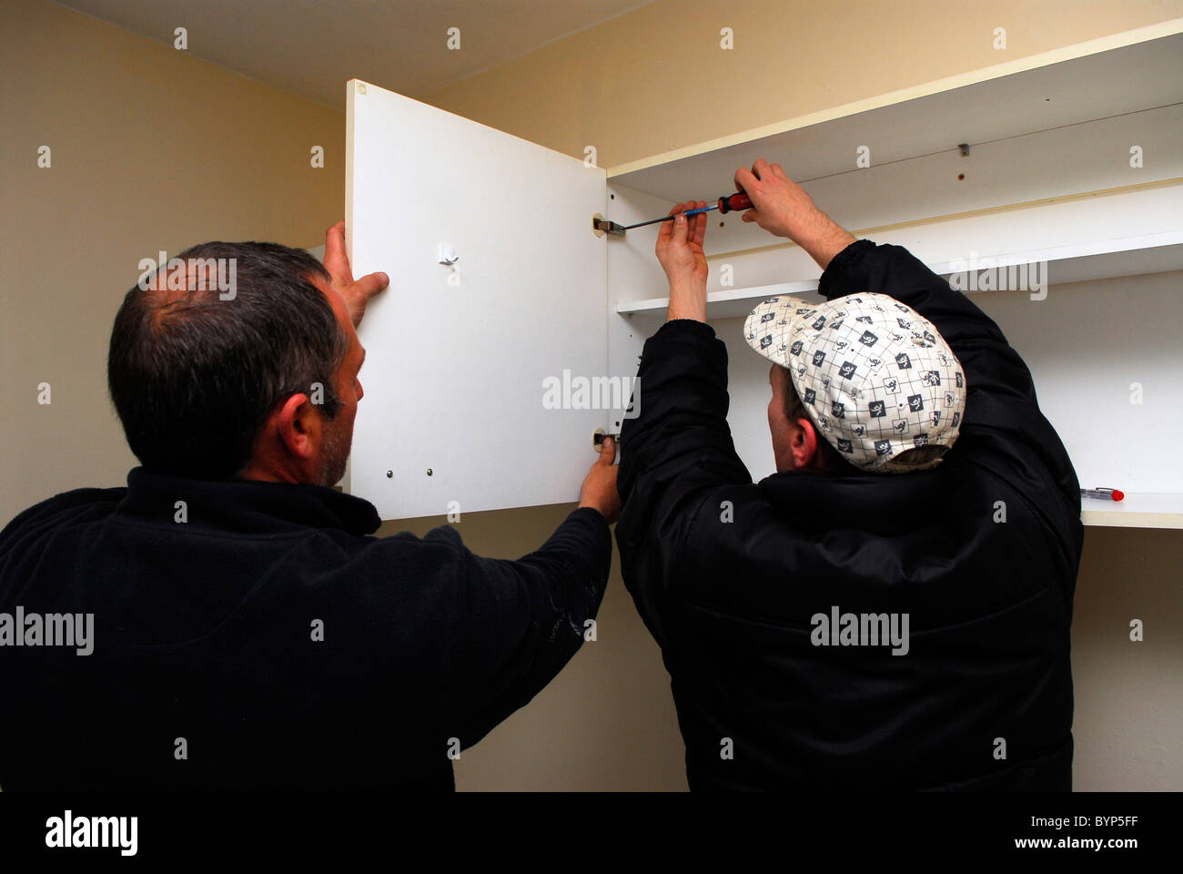 Men fixing kitchen unit in top floor flat, Bristol, UK Stock Photo Alamy