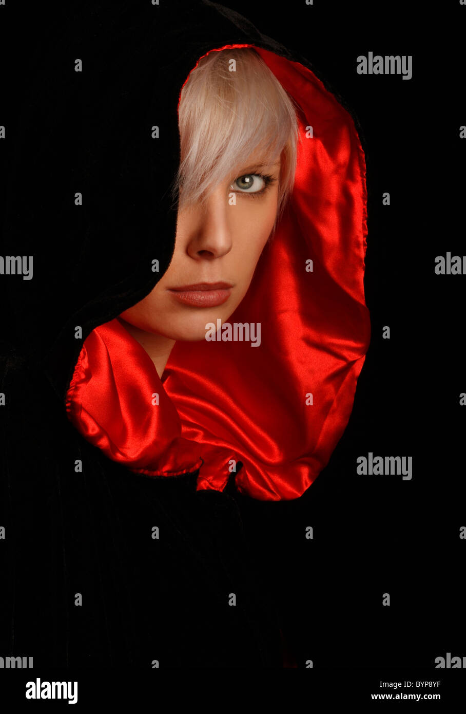 young silver haired woman wearing a red lined black cloak Stock Photo