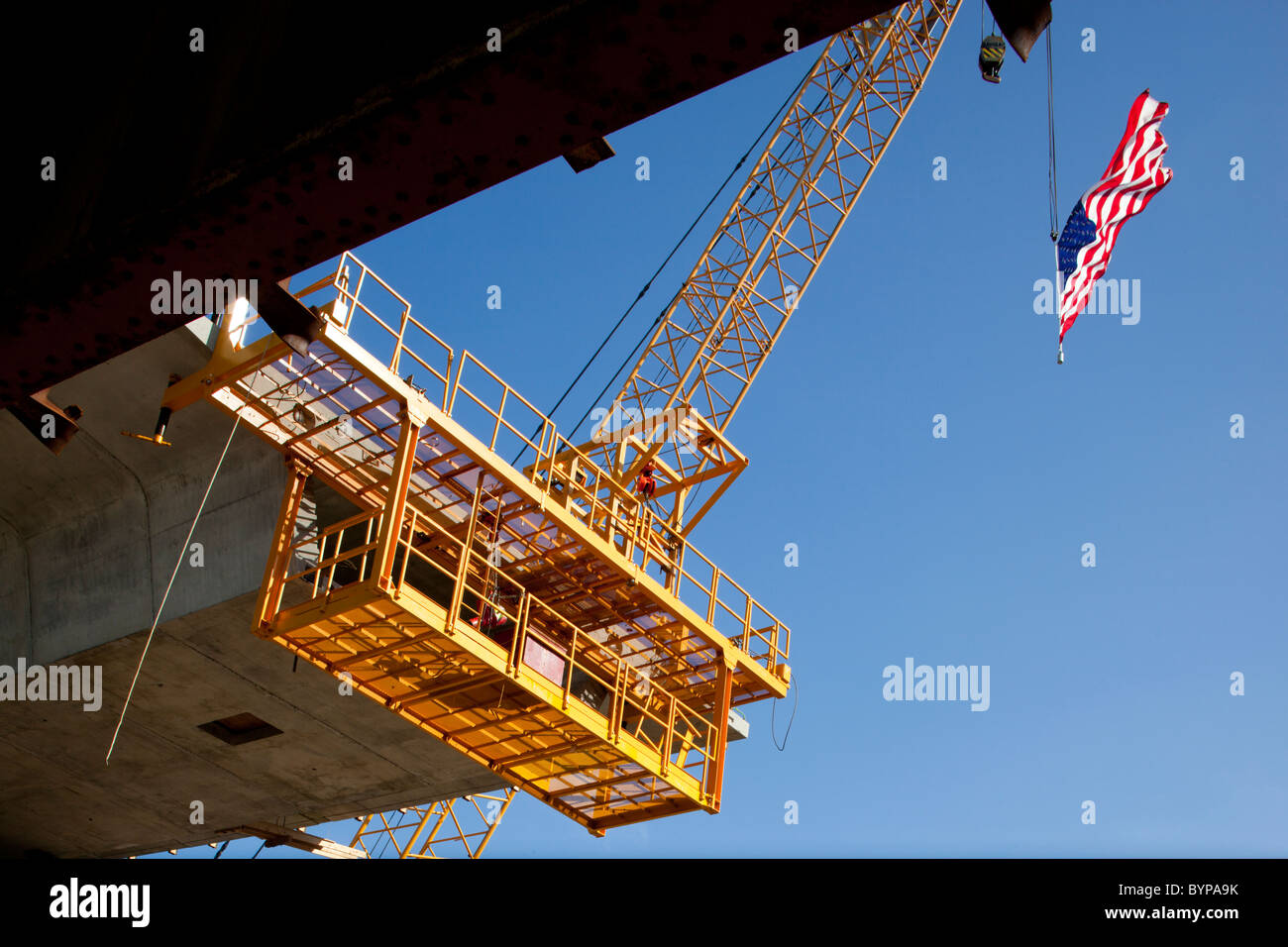 USA, New Jersey, Perth Amboy, American flag flies from crane above bridge construction site along Jersey Shore Stock Photo