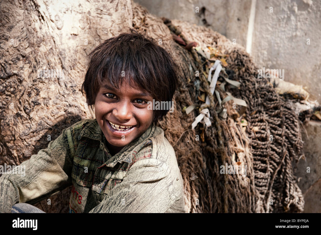 Happy young poor lower caste Indian street boy smiling leaning against