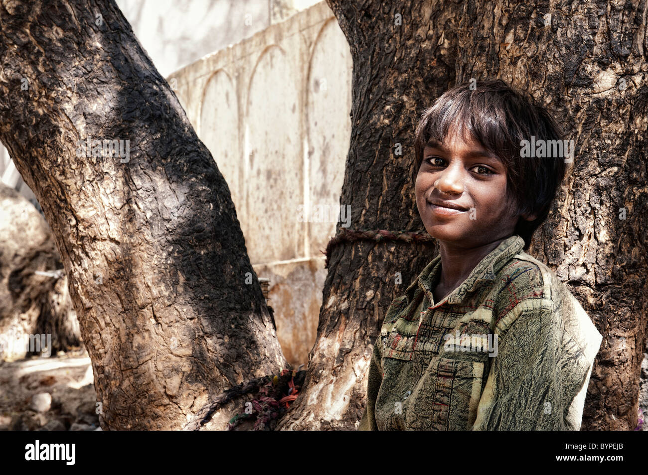 Happy young poor lower caste Indian street boy smiling leaning against