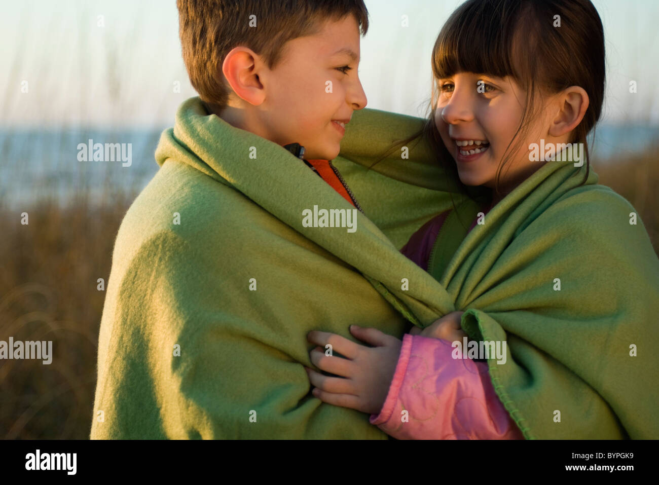 Children wrapped together in blanket outdoors, portrait Stock Photo Alamy