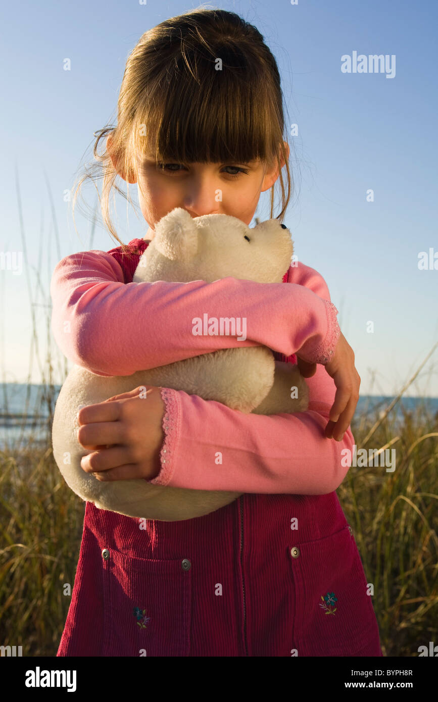 Young girl hugging stuffed toy polar bear cub Stock Photo