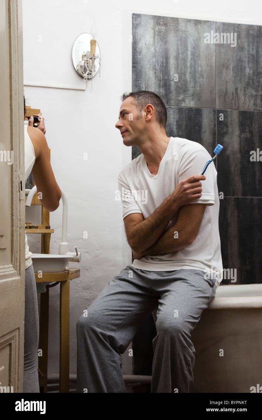 Husband waiting in bathroom while wife applies make-up Stock Photo