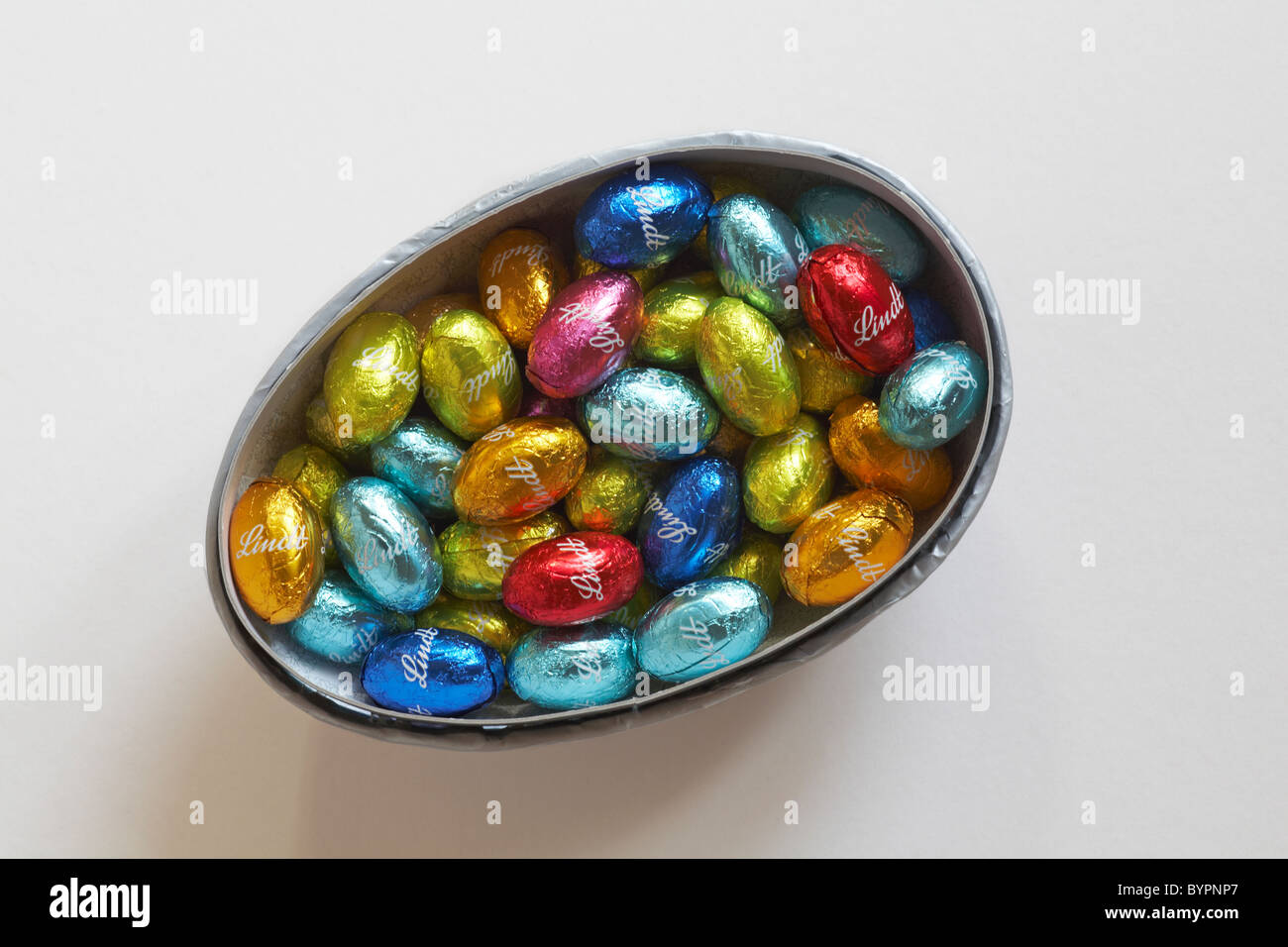Lindt miniature easter eggs in coloured foil wrappers in easter egg half container Stock Photo