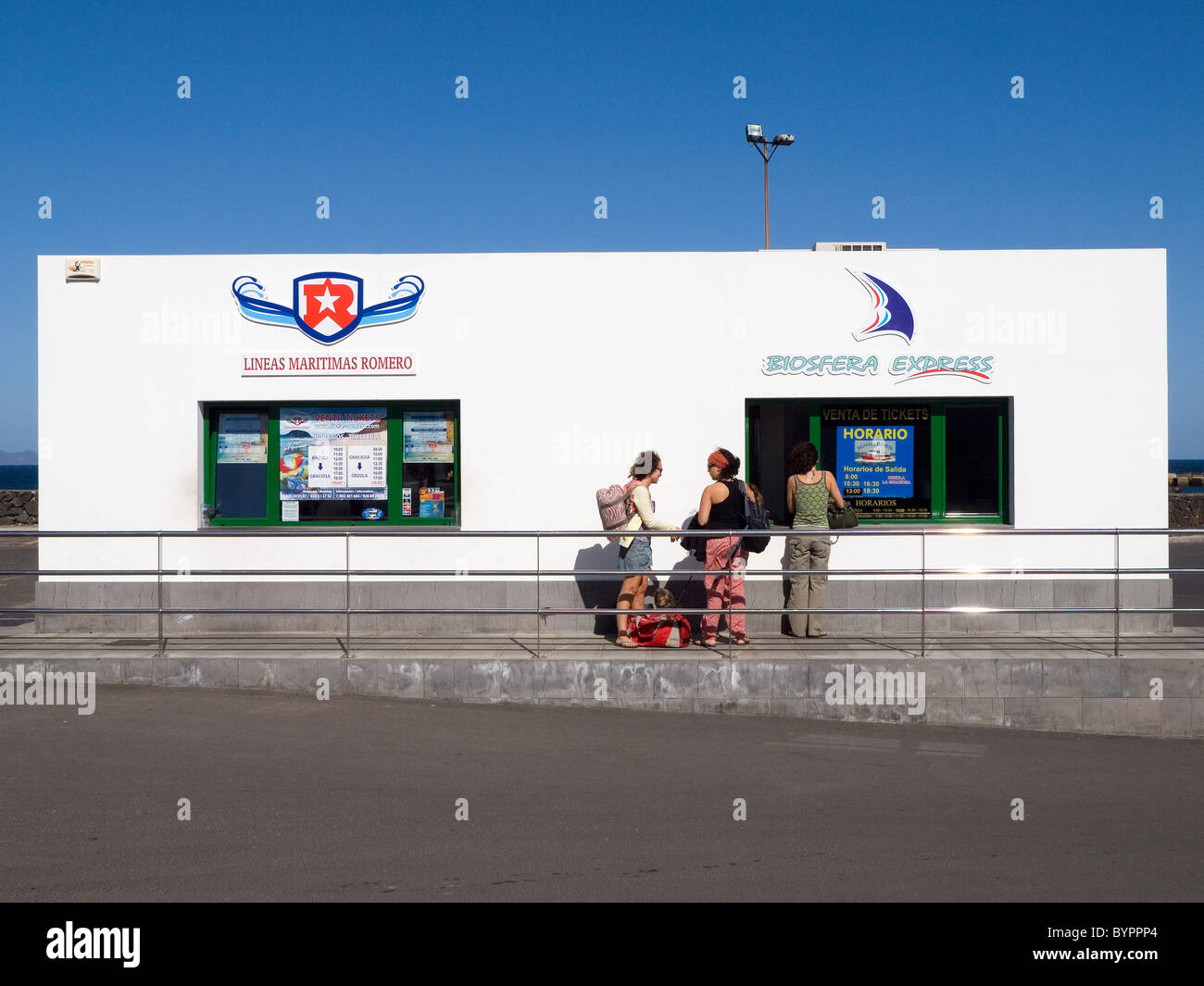Three young women at ticket office of Lineas Maritimas Romero in Orzola Lanzarote for the ferry to the island of La Graciosa Stock Photo