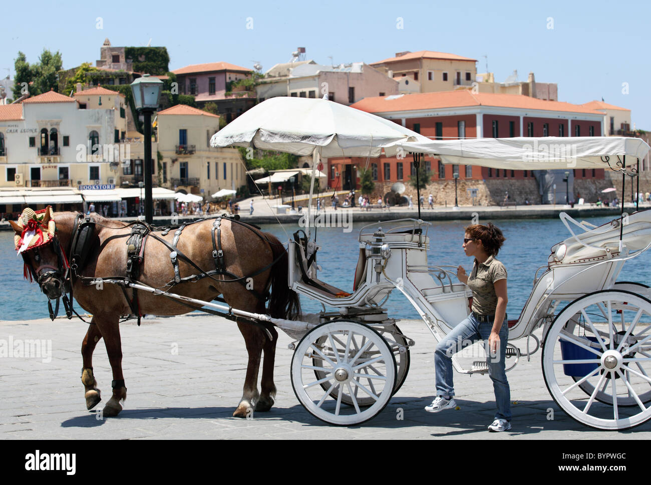 A buggy driver and her horse wait on the quay for customers for a tour round Chania Old Town. Stock Photo