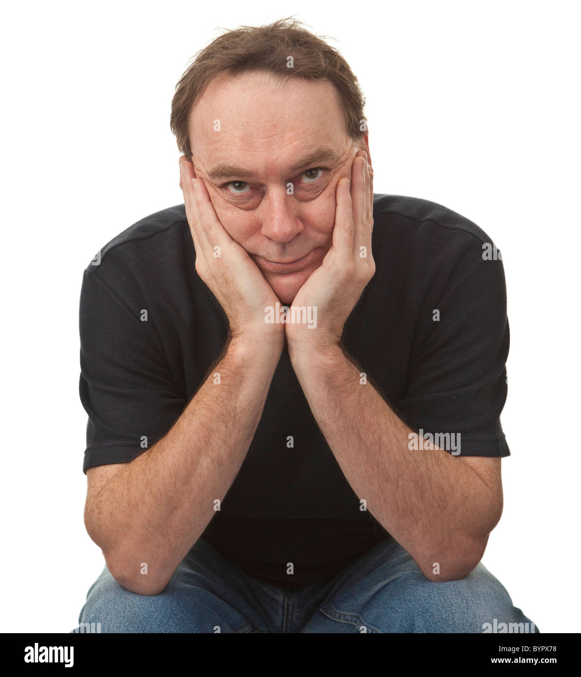 adult man sat with his head in his hands glancing upwards, he is casually dressed and isolated against a white background Stock Photo