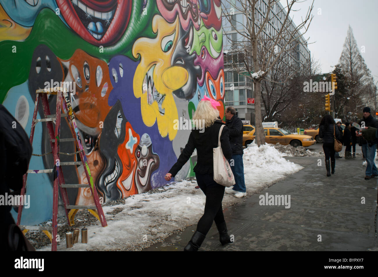 A pedestrian strolls by a mural by the artist Kenny Scharf at the corner of Bowery and Houston Street in New York Stock Photo