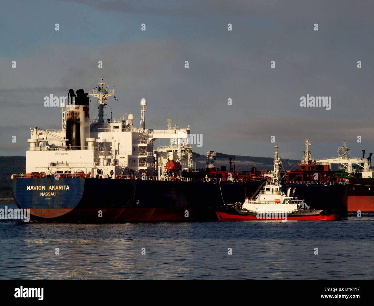 A tug maneuvers a Tanker at the Nigg Oil Terminal, Cromarty Firth, Scotland Stock Photo
