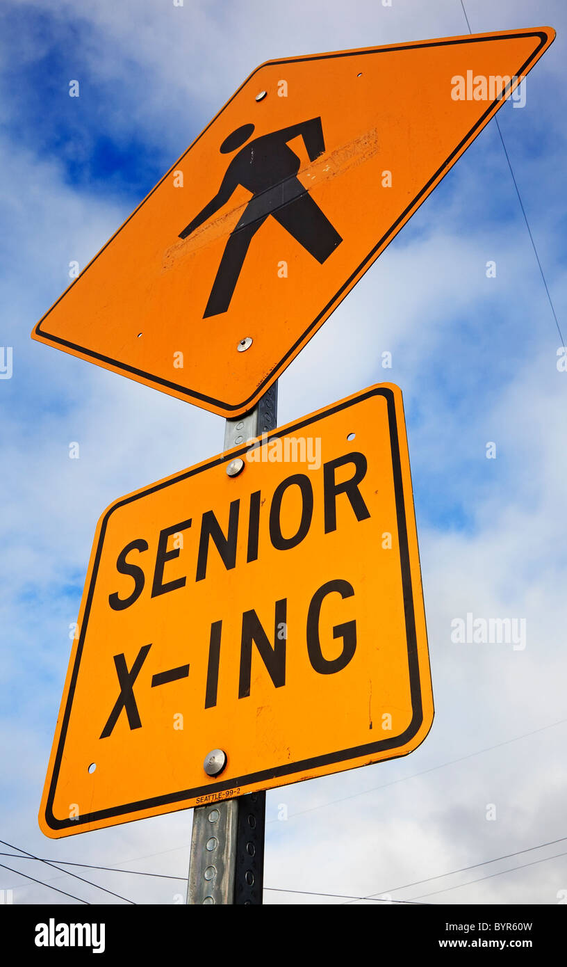 senior crossing sign against cloudy sky Stock Photo