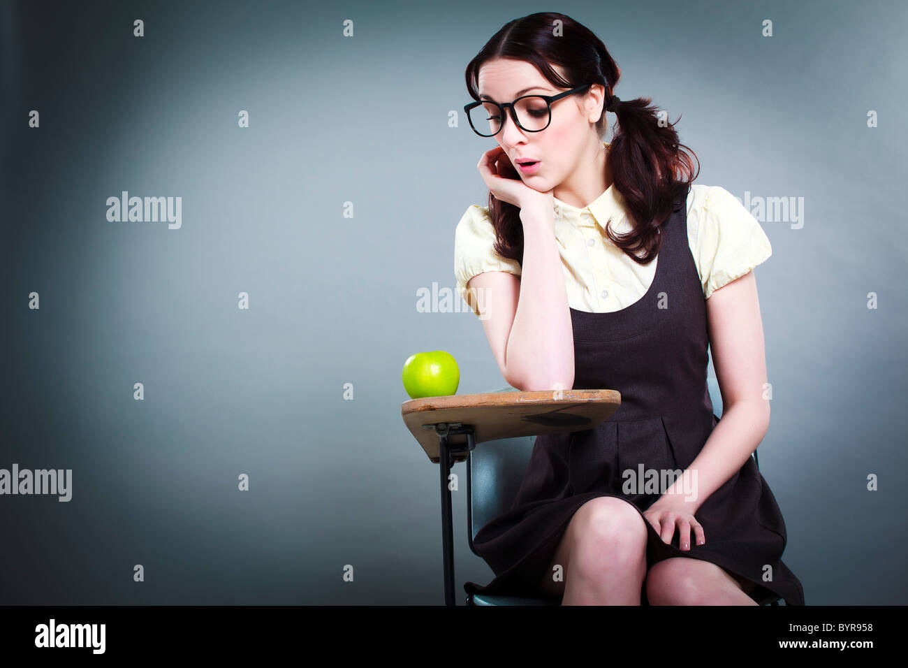 geeky school girl peers at apple on her desk Stock Photo - Alamy