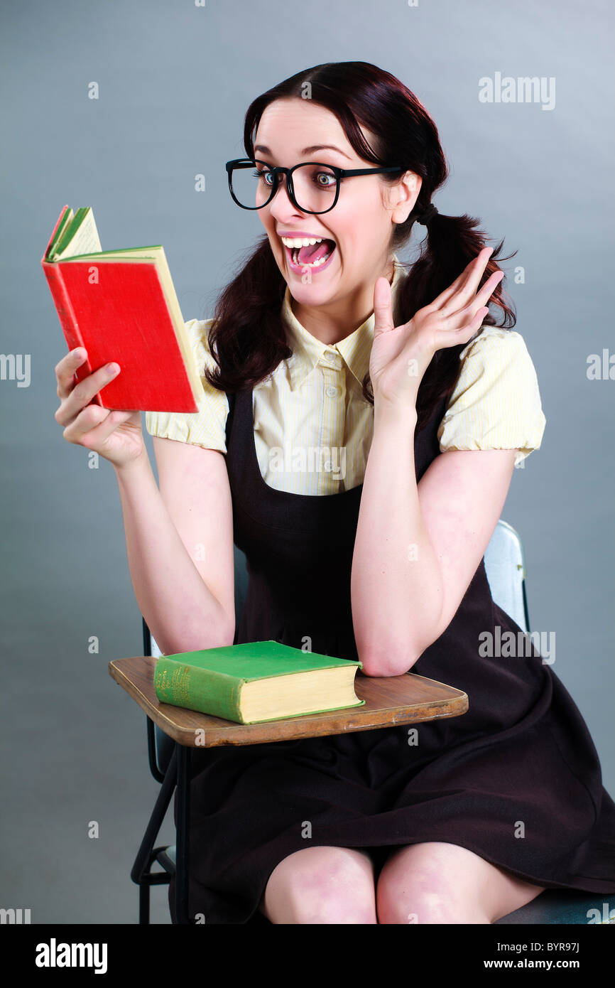 delighted geeky school girl reading a book at her desk Stock Photo - Alamy