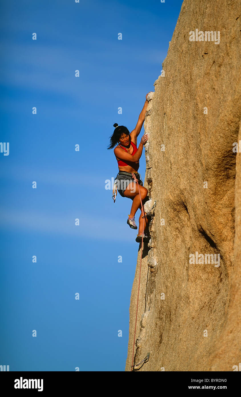 Female rock climber struggles for her next grip as she battles her way