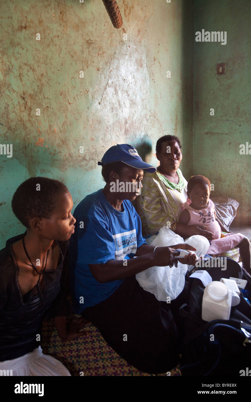 A home health care worker with the NGO Living Goods makes a visit to a woman and her children suffering from malaria in Kampala. Stock Photo