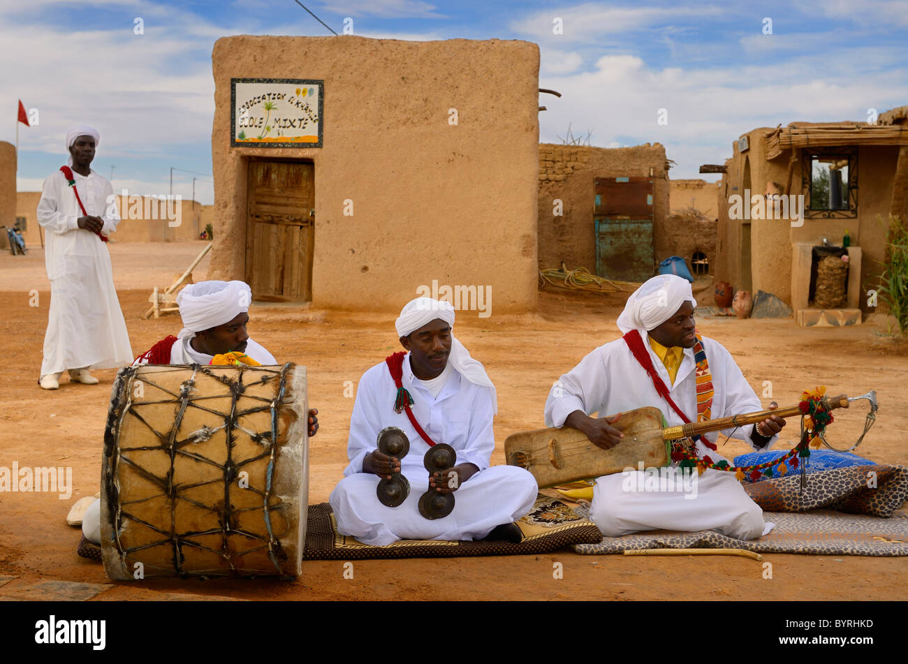 Gnawa music group in white turbans and jellabas sitting and playing music in Khemliya desert village Morocco North Africa Stock Photo