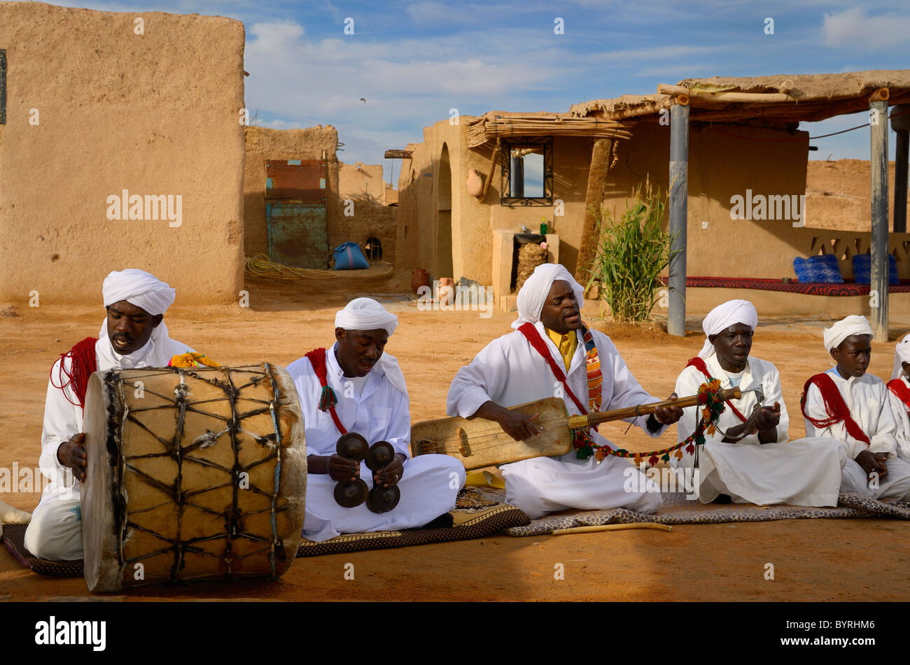 Khemliya Gnawa musicians in white turbans and jellabas playing while sitting in a desert village Khemliya Morocco Stock Photo