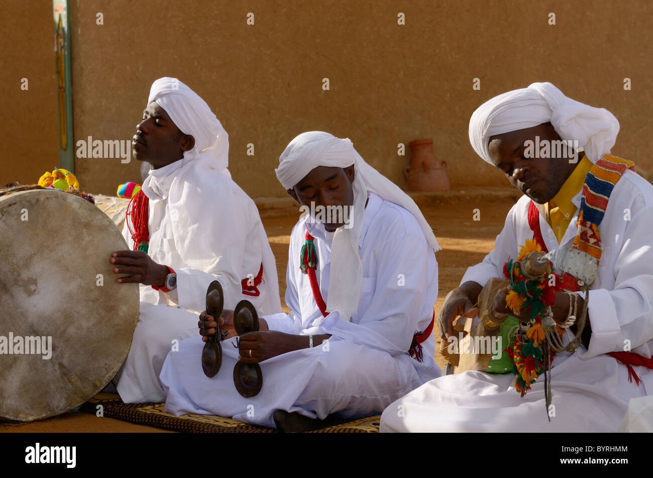Eyes closed Gnawa musicians playing music in trance in white robes and headdress with tbel hajhuj and krakeb in Khemliya village Morocco North Africa Stock Photo