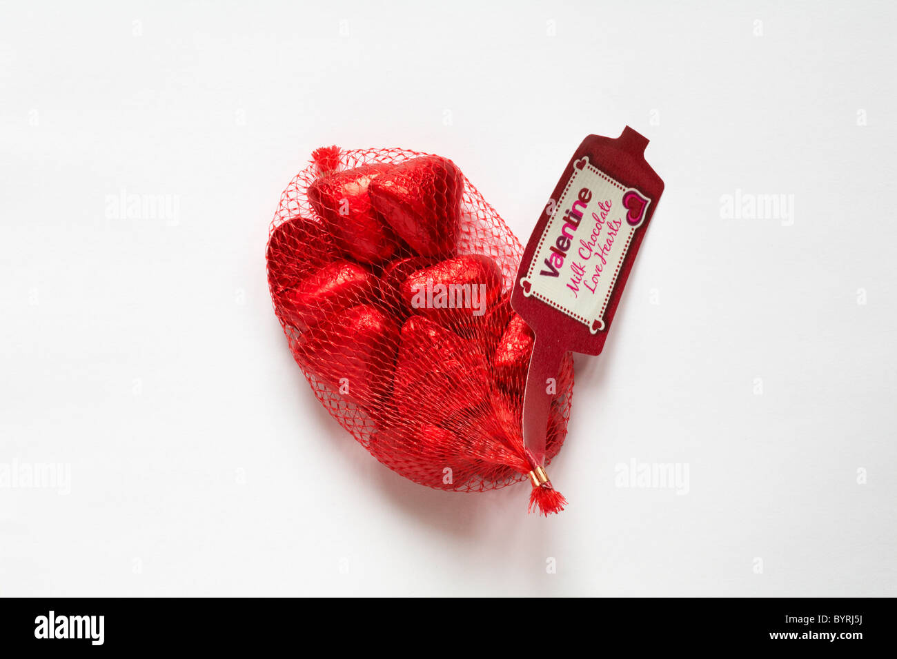 Nettng of Valentine milk chocolate love hearts - chocolate hearts in red foil on white background - ideal present for Valentine day, Valentines day Stock Photo