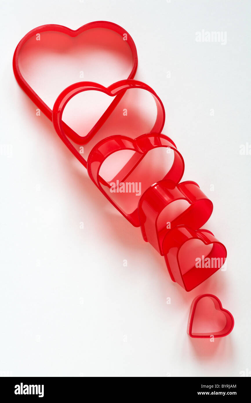 Stack of red Valentine heart cutters decreasing in size isolated on white background - concept falling out of love Stock Photo