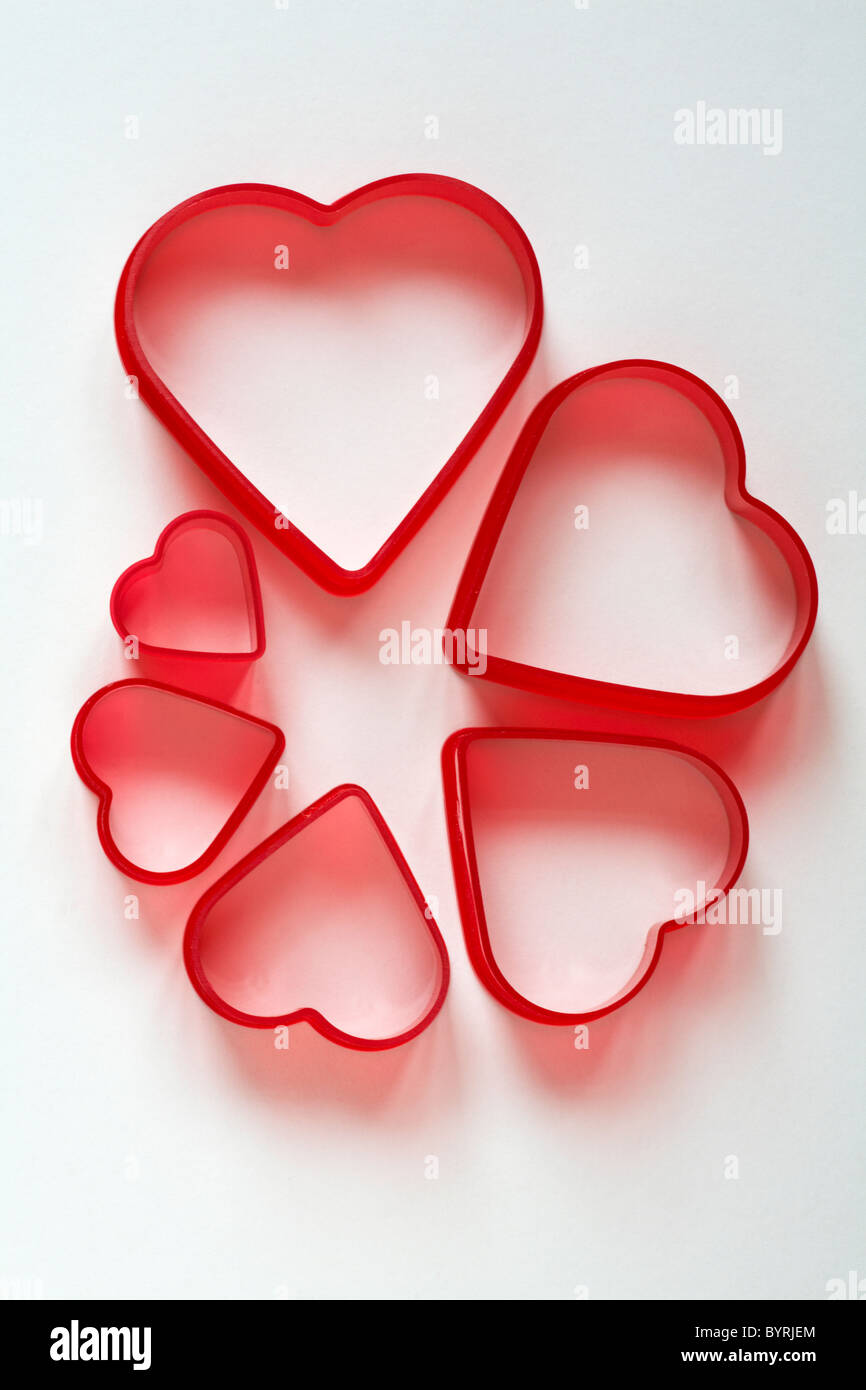 Red heart shaped cutters decreasing in size set against white background Stock Photo