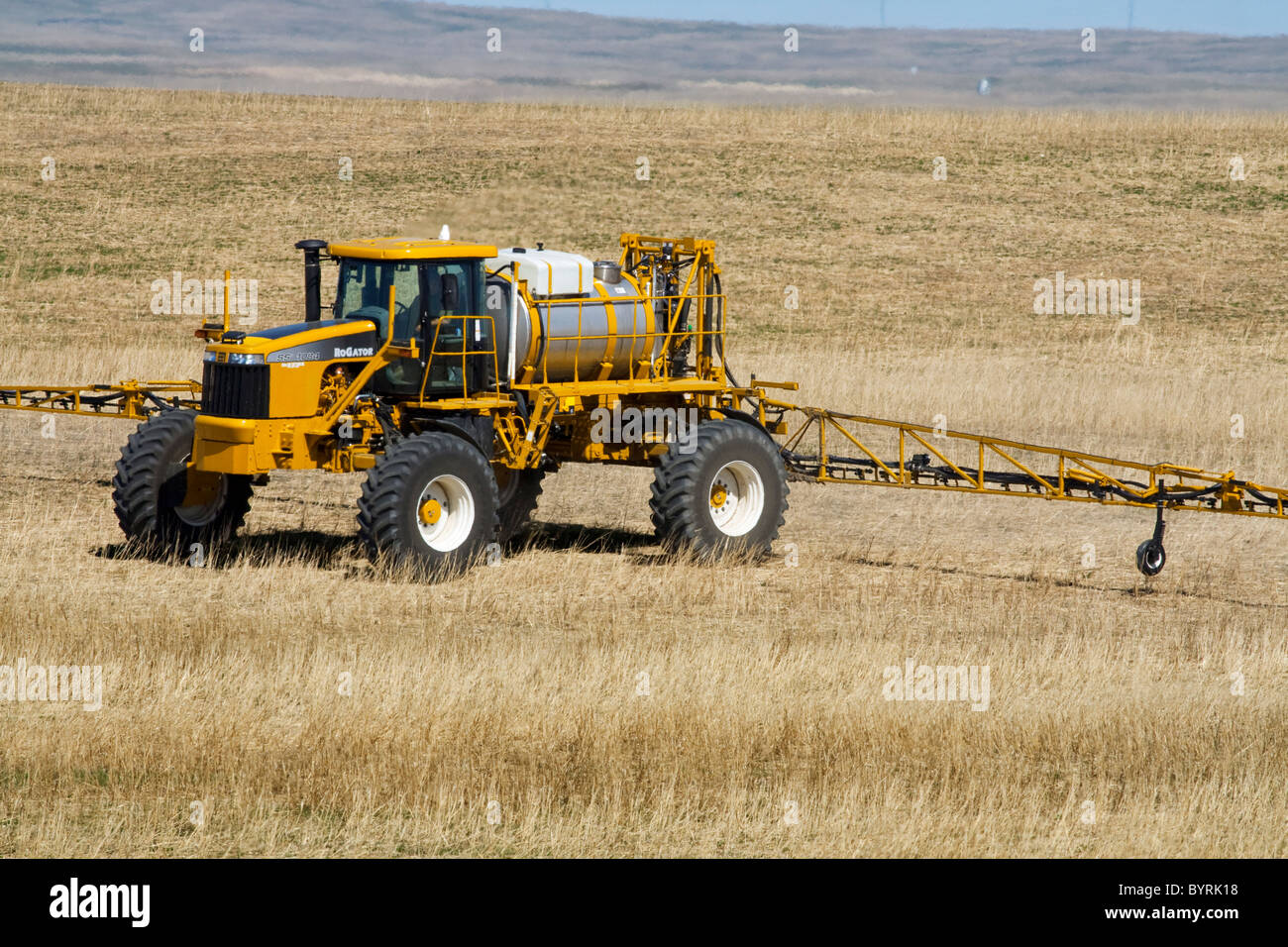 A RoGator applies herbicide to a dryland grain field in Spring prior to planting a new grain crop / Alberta, Canada. Stock Photo
