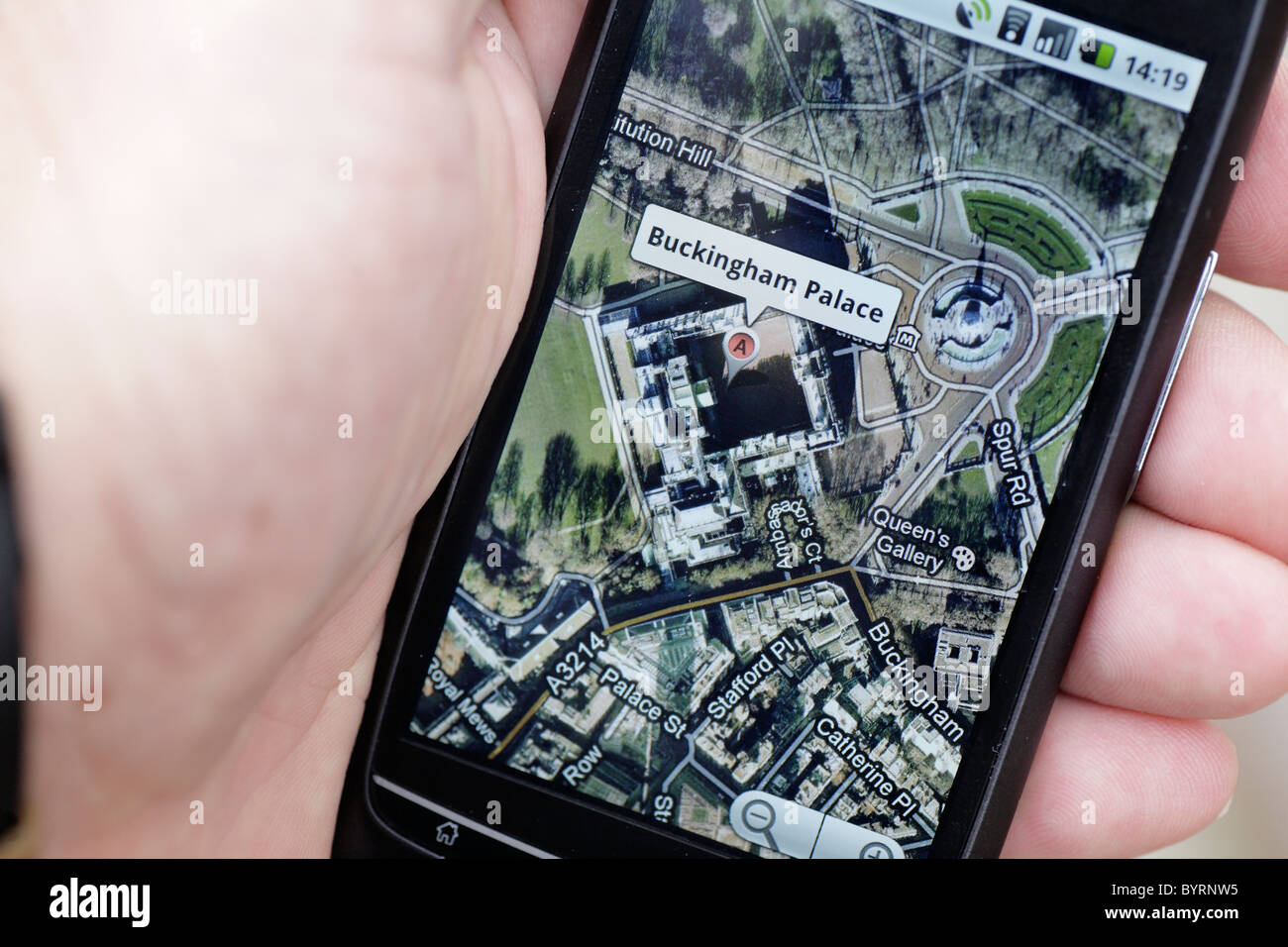 Man looking at google GPS maps map of Buckingham Palace London on a touch screen smartphone in a wifi hotspot closeup Stock Photo