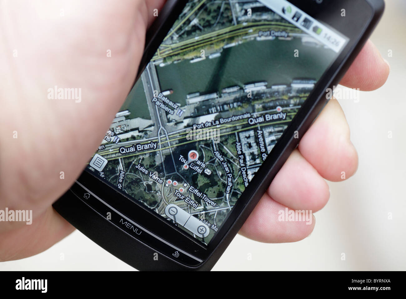 Man looking at google GPS maps map of Paris Eiffel Tower on a touch screen smartphone in a wifi hotspot closeup shadow of tower Stock Photo