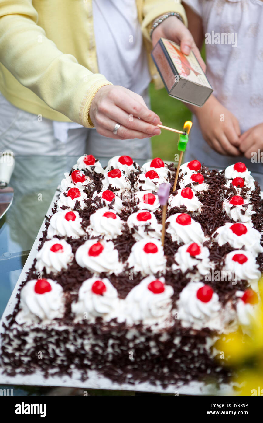 A woman lighting a candle on a birthday cake Stock Photo - Alamy