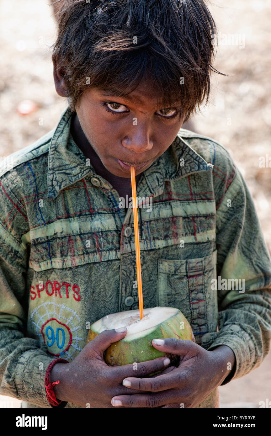 Happy young poor lower caste Indian street boy drinking coconut water. Andhra Pradesh, India Stock Photo