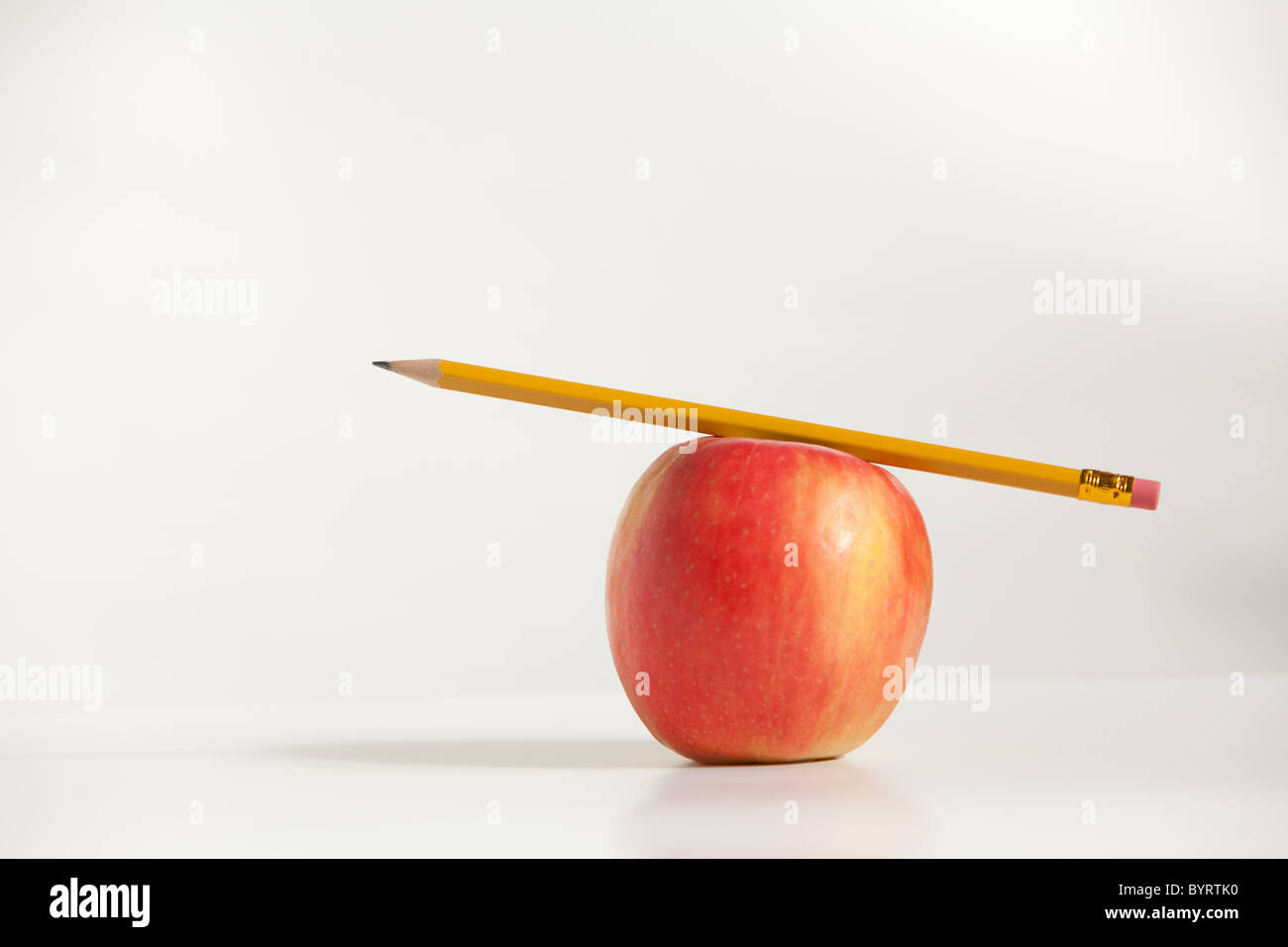 A Pencil on top of An Apple in the studio Stock Photo