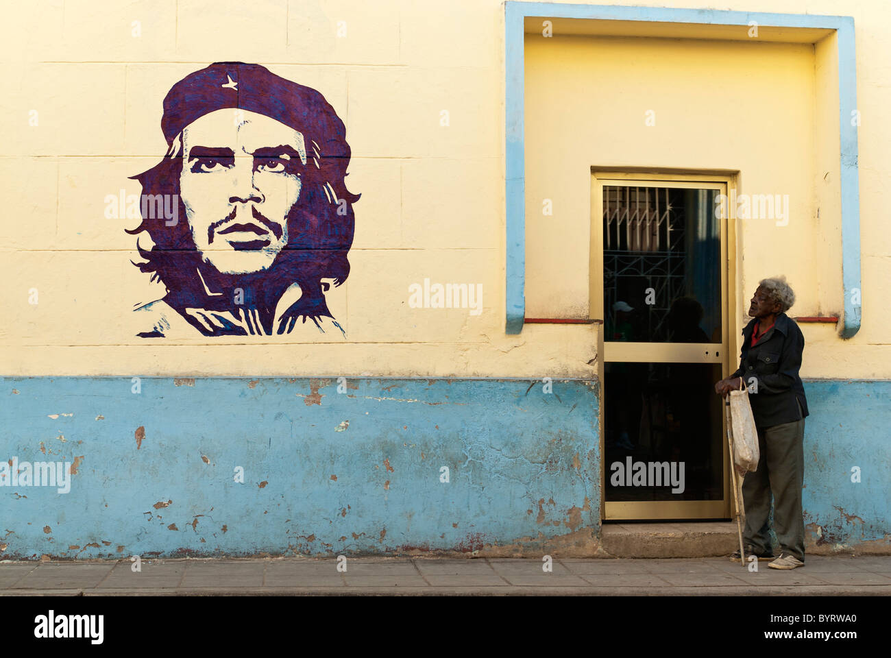 Old woman close to a painting of Che Guevara, Camaguey, Cuba, Caribbean. Stock Photo