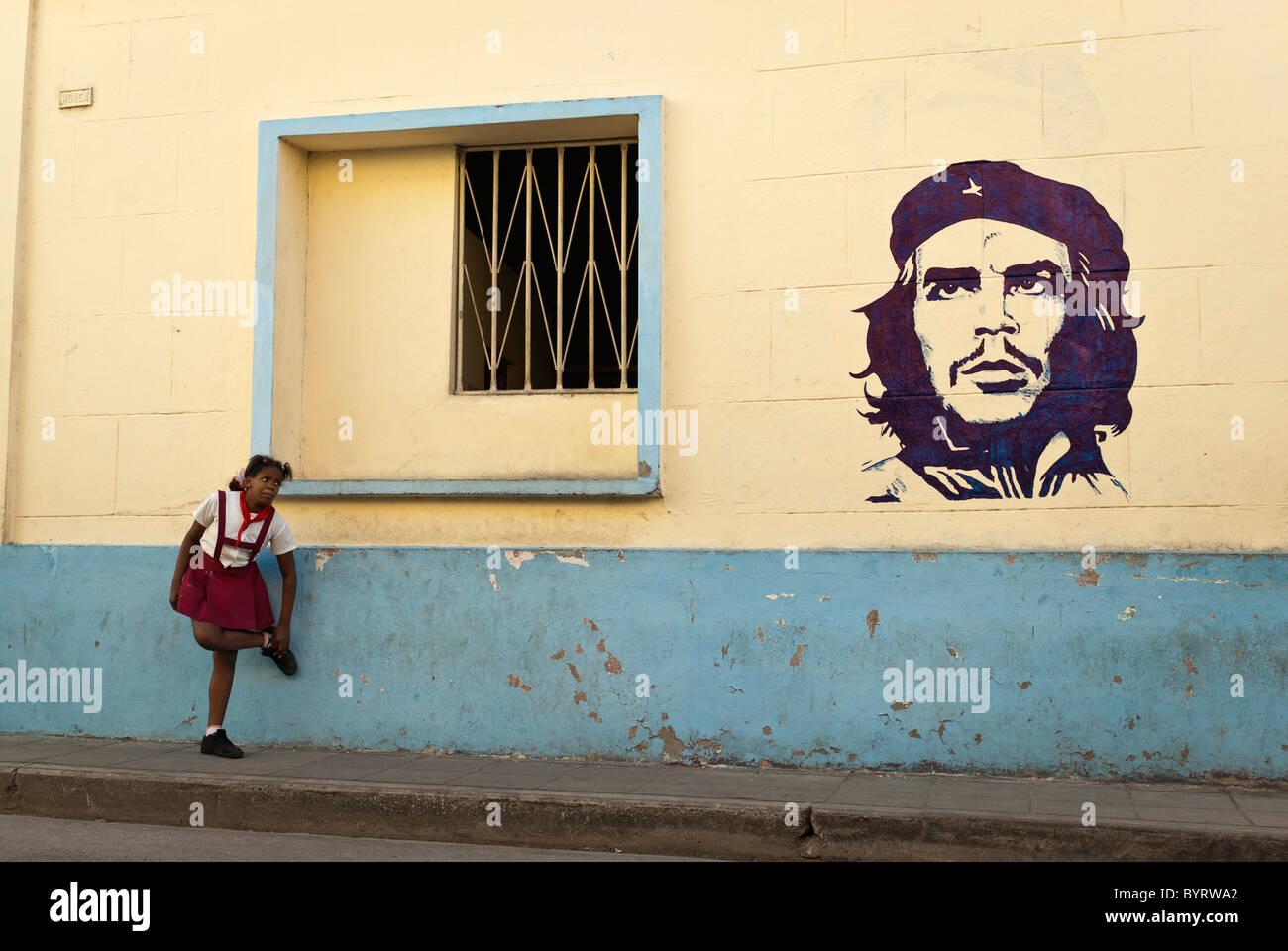 Girl in a school uniform close to a painting of Che Guevara, Camaguey, Cuba, Caribbean. Stock Photo