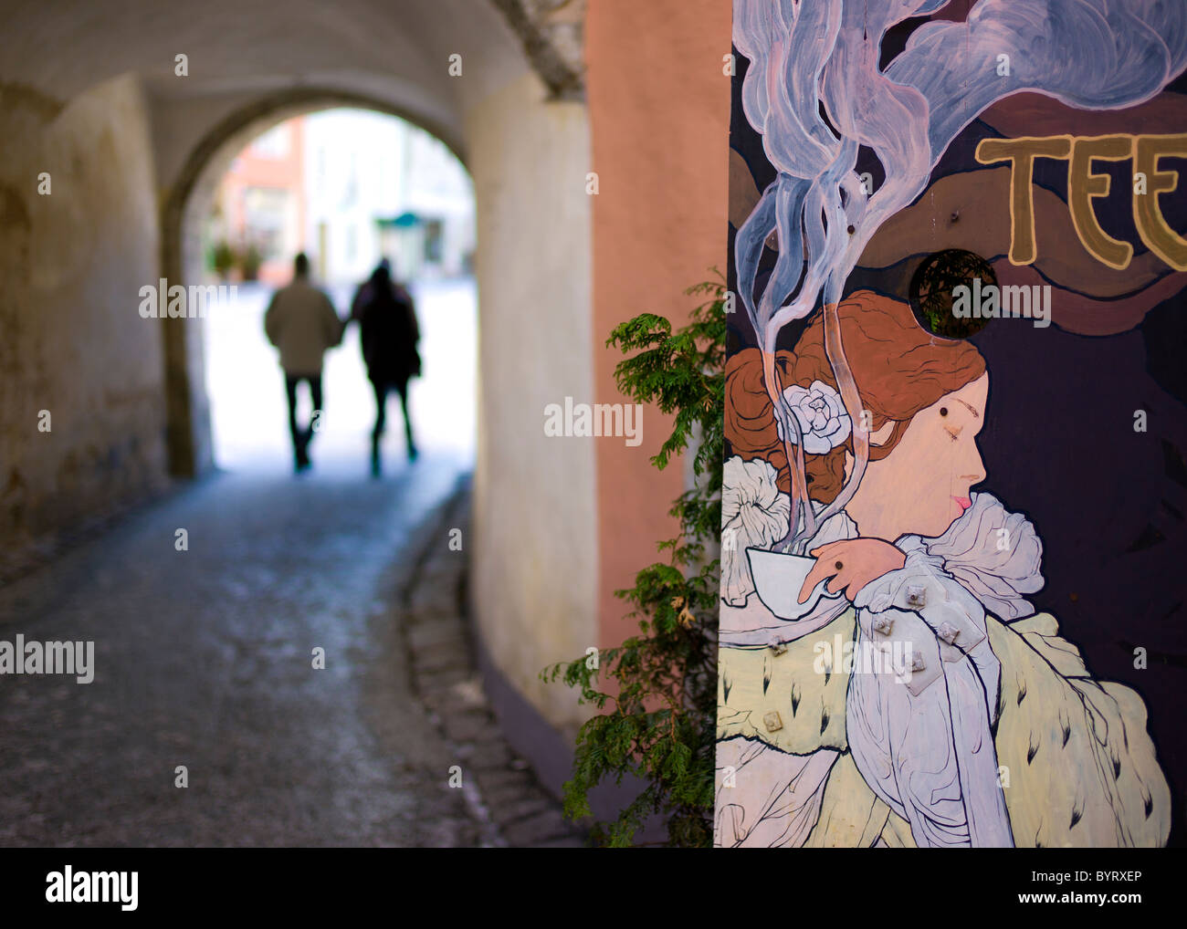 A Tallinn café sign with tourists walking through a passageway in the background Stock Photo