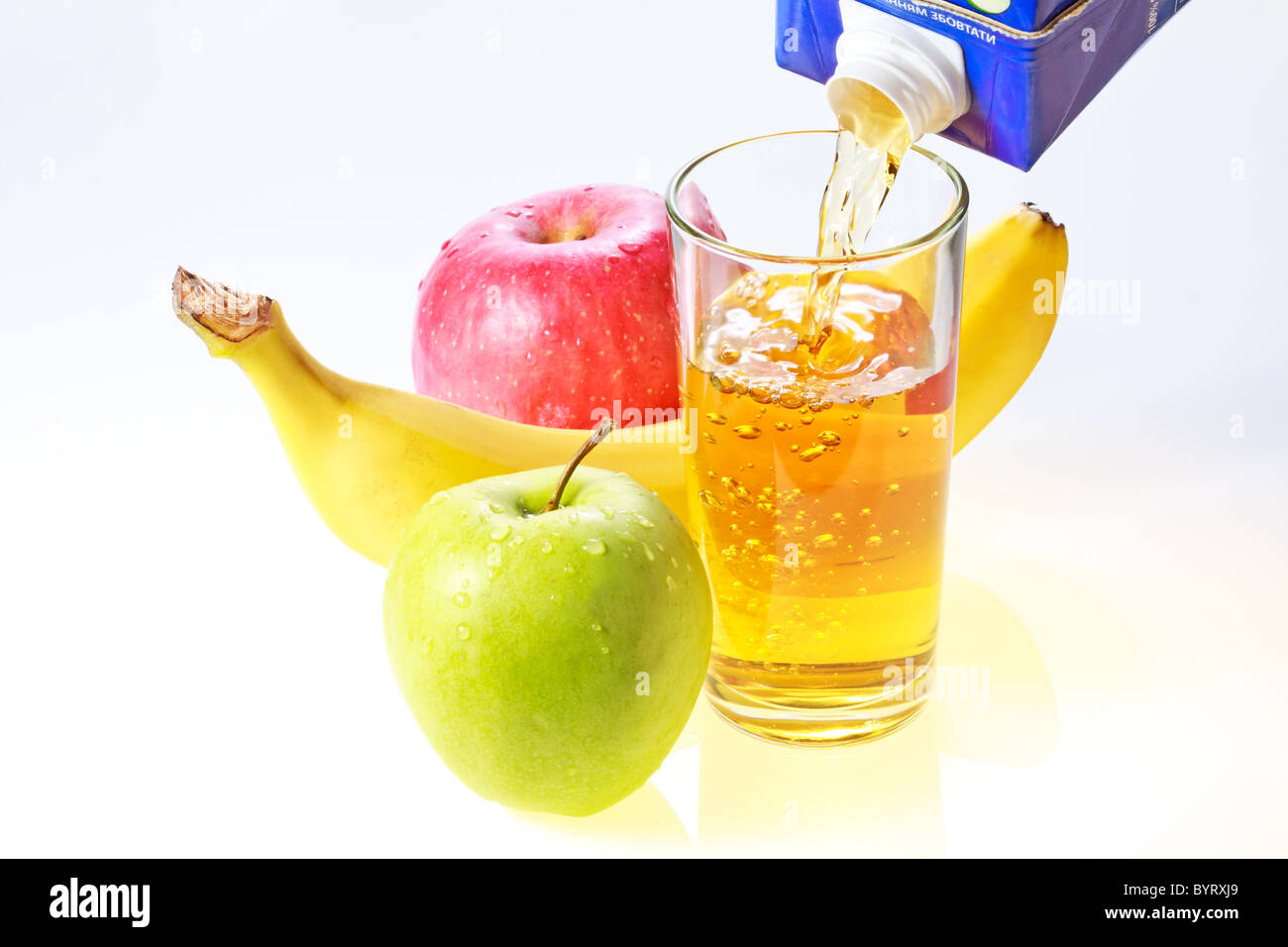Banana, green and red apples and glass filling with apple juice Stock