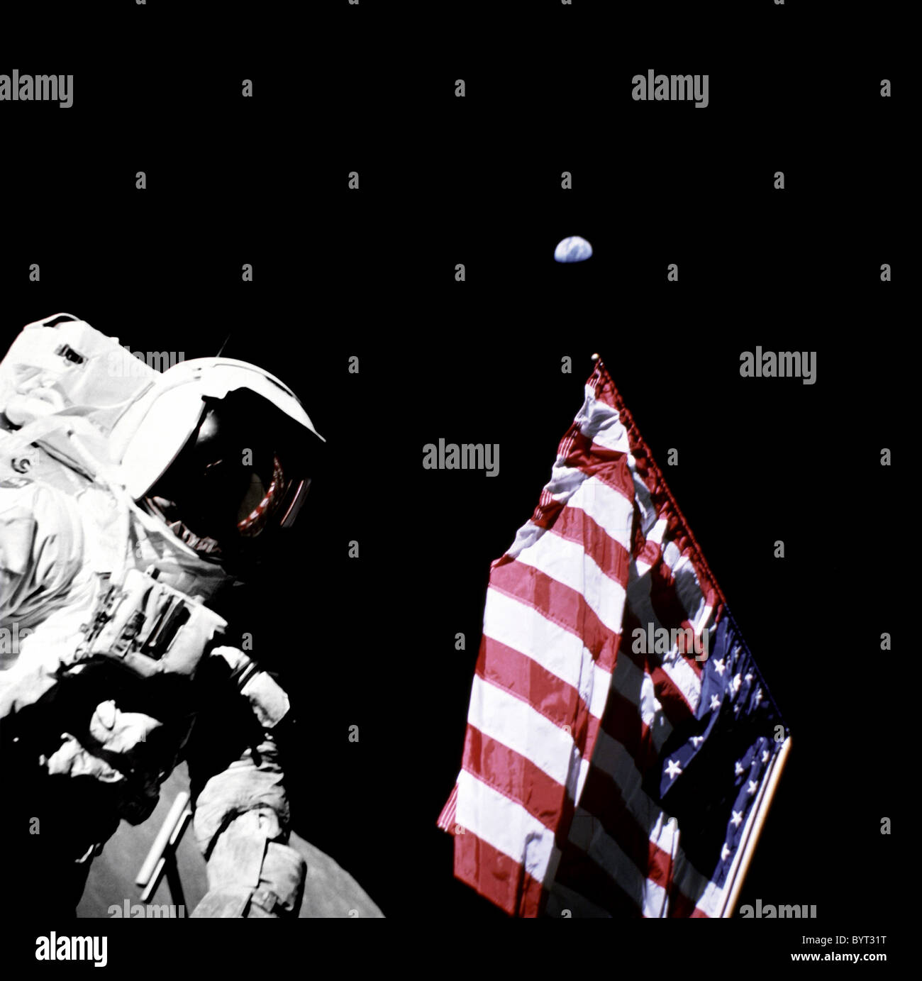 Apollo 17 Geologist and Astronaut Harrison Schmitt next to the U.S. flag with the Earth behind. Stock Photo