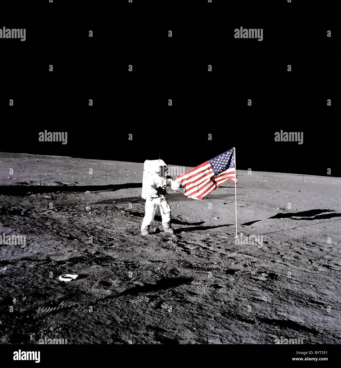 Apollo 12 astronaut Charles 'Pete' Conrad stands beside the United States flag on the moon. Stock Photo