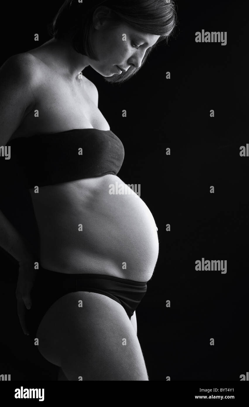 Five Month Pregnant Lady against Black Background Stock Photo