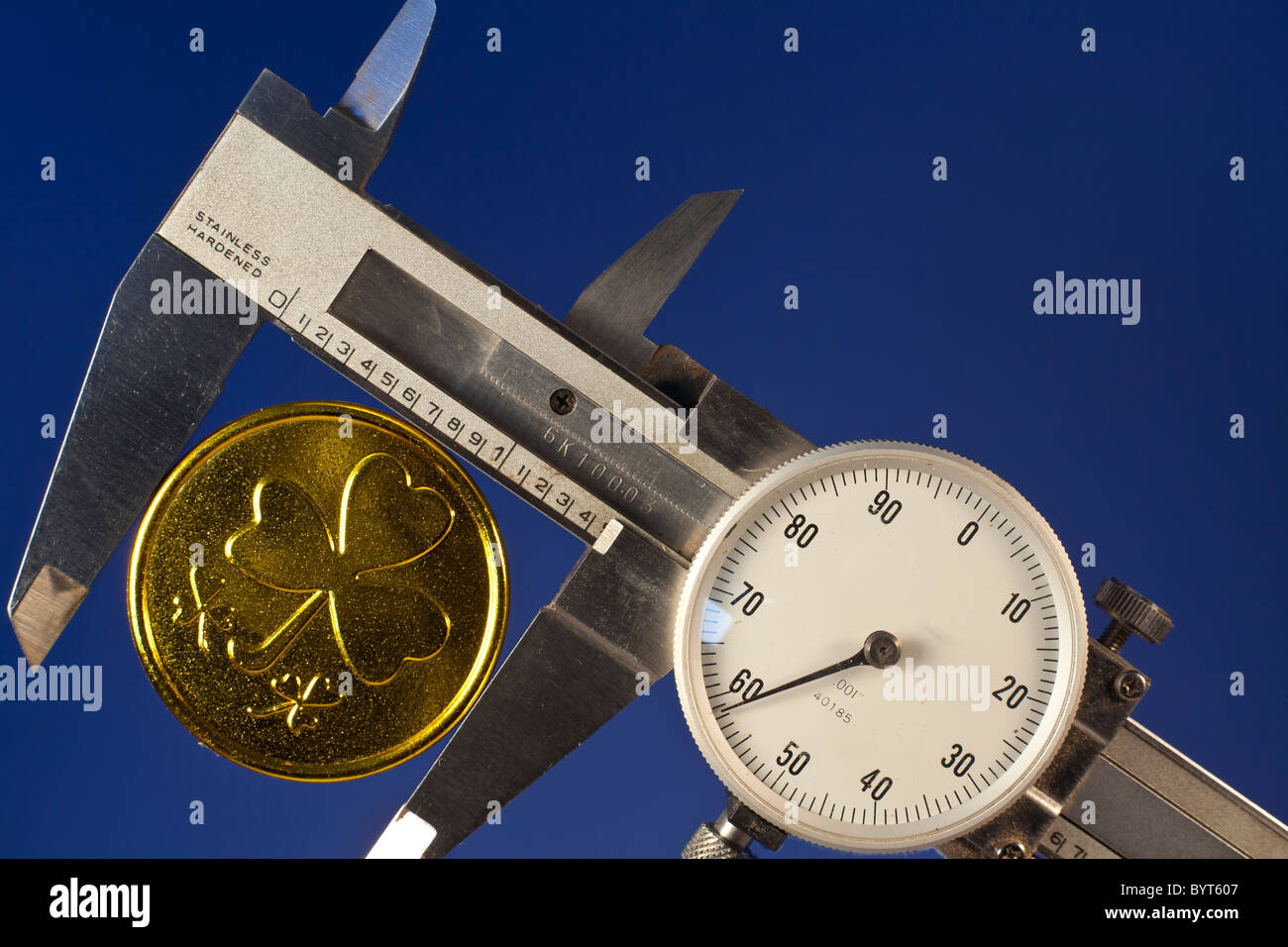 A machinists caliper with a fake gold coin Stock Photo
