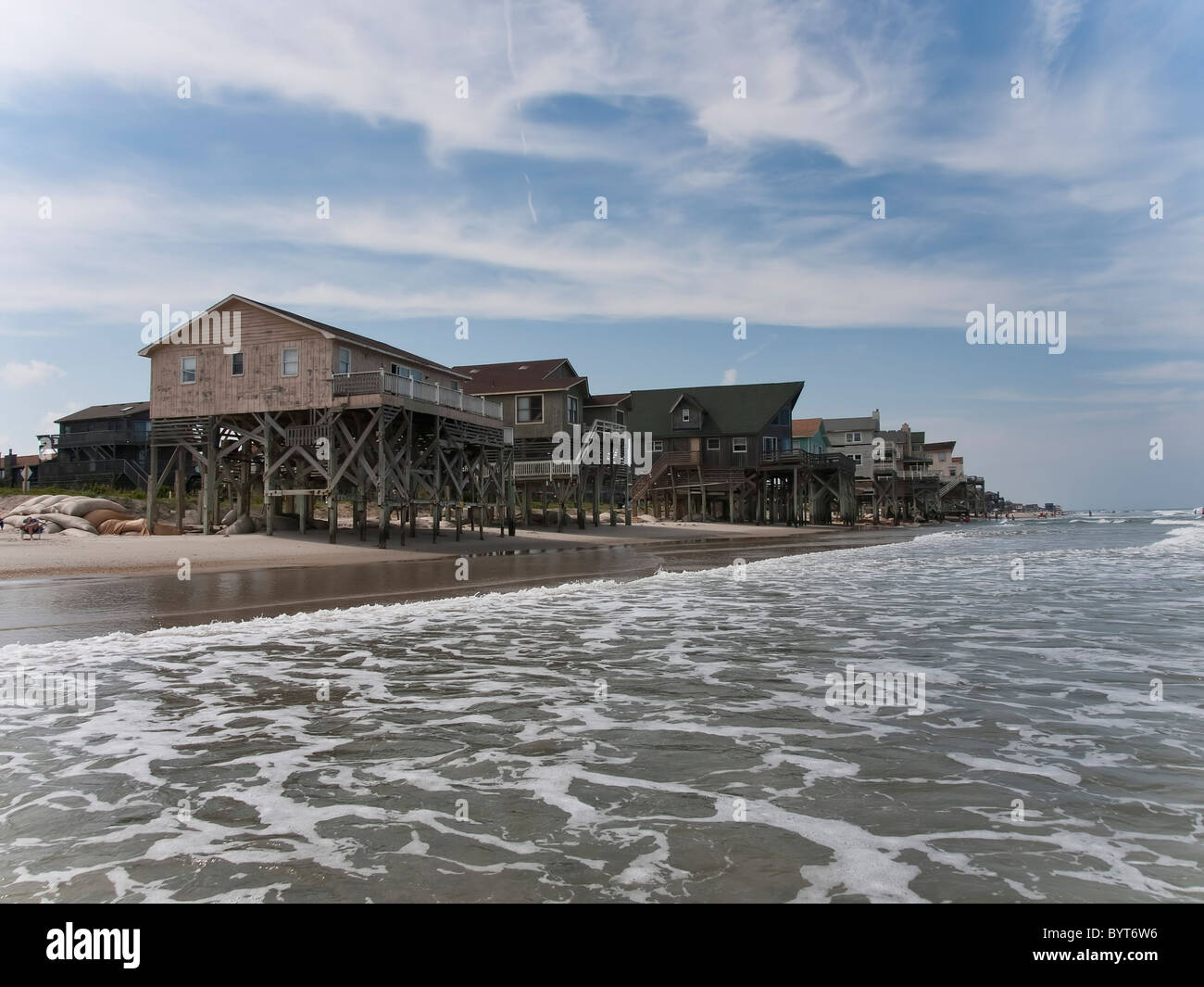 Wooden vacation homes line the beach on Nags Head. The beach has eroded away and the homed are condemned Stock Photo