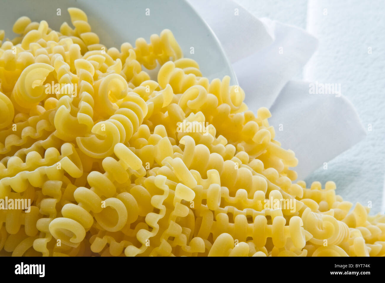 Uncooked riccioli pasta with with bowl and napkin Stock Photo