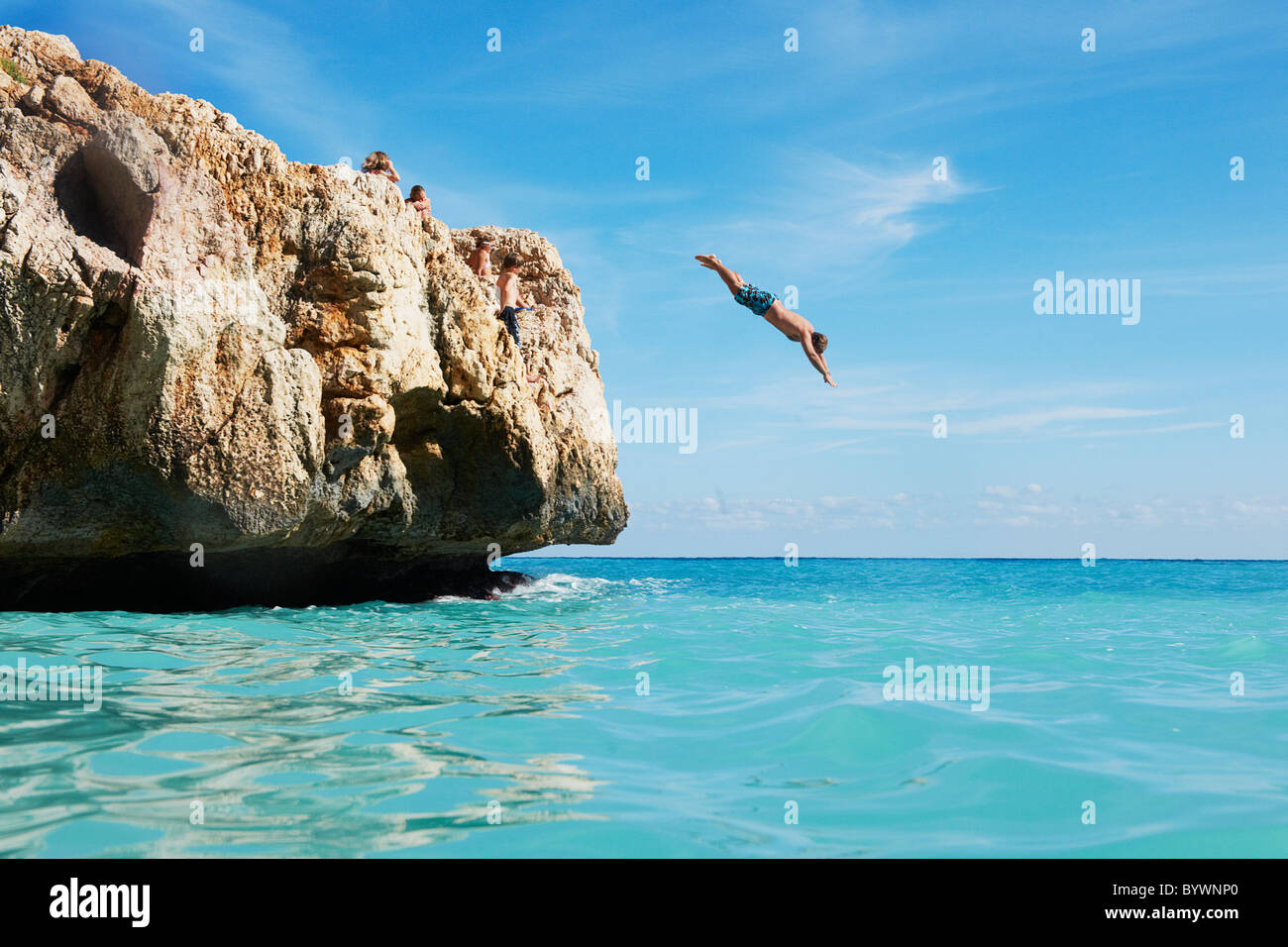 Man diving from rocks into the sea Stock Photo