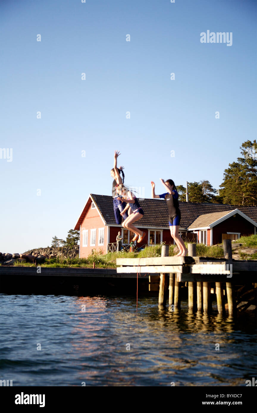 Girls jumping into Baltic, near Degerby, Foglo, Aland Islands, Finland. Model released Stock Photo