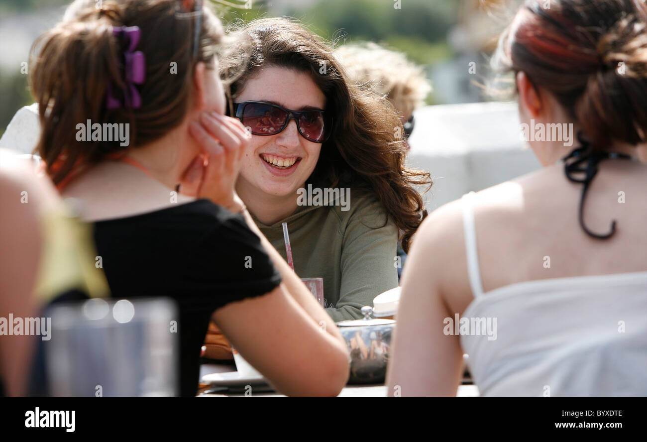 A group of girls socialising and enjoying a drink at a bar outside in ...