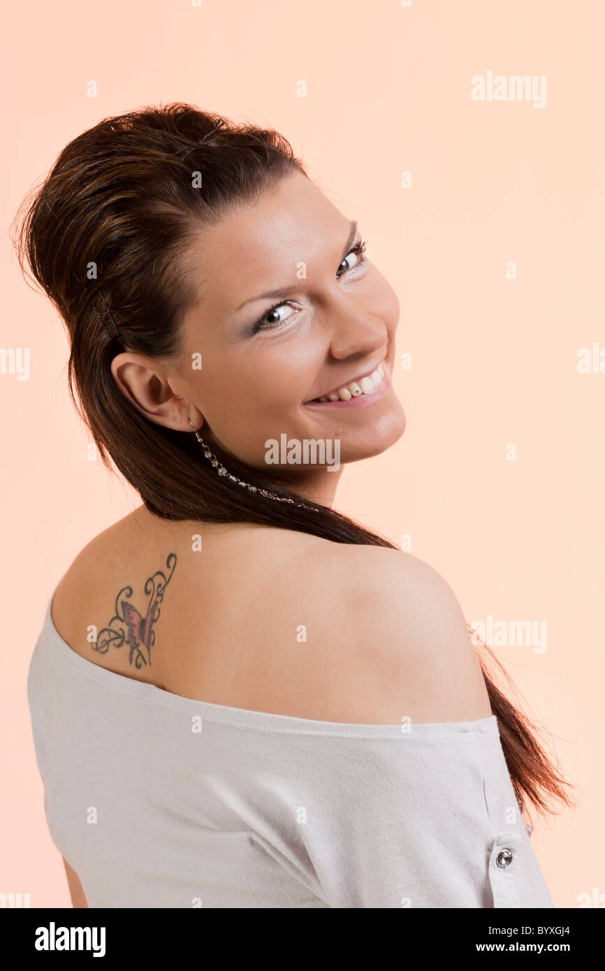 A dark-haired smiling young woman with a tattoo on her back Stock Photo