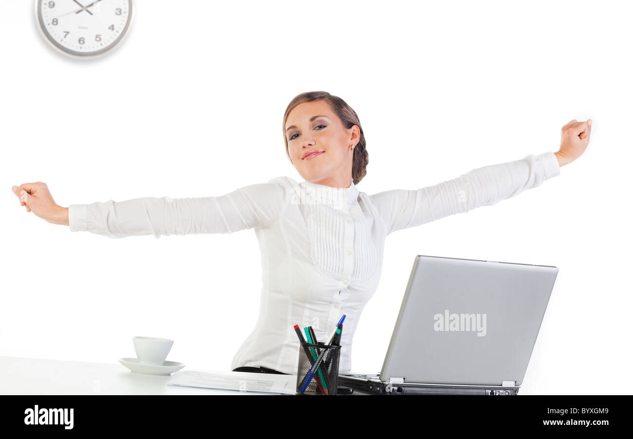Pretty young businesswoman stretching her hands while sitting at her desk Stock Photo