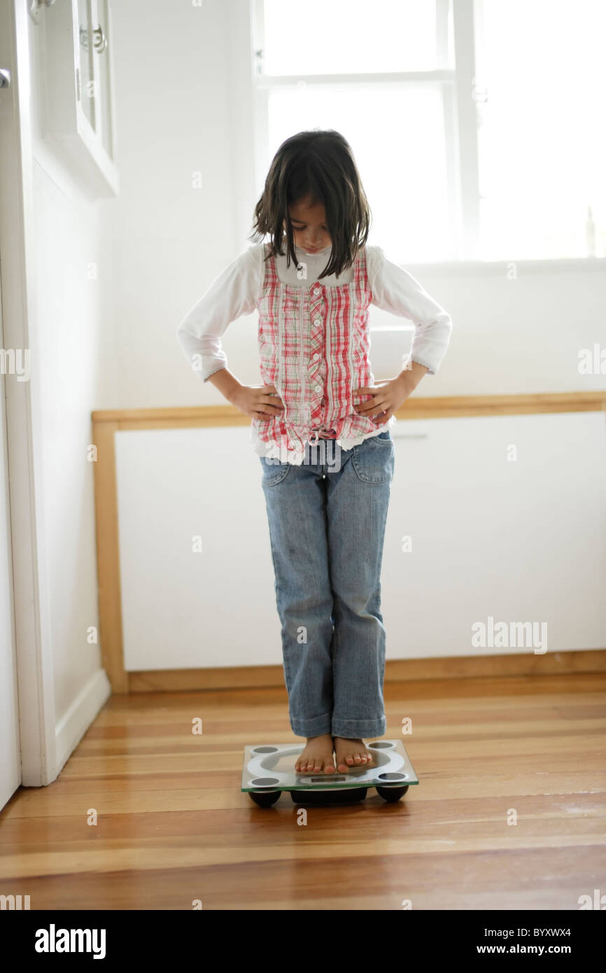 Girl weighs herself with bathroom scales Stock Photo