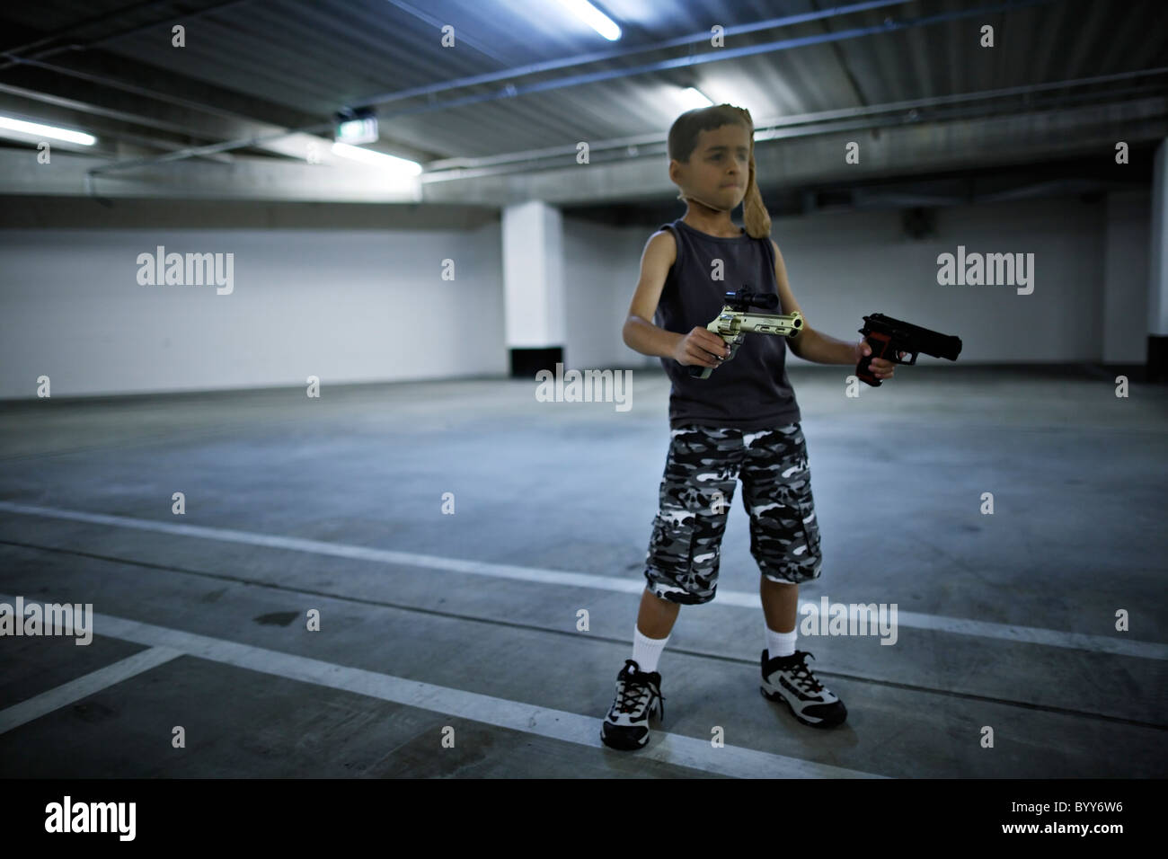 Children with stocking masks and toy guns in underground carpark prepare for big hold-up. Stock Photo